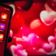 Telefon z ikonami aplikacji randkowych: Tinder, Badoo, W-Match. Tło w serduszka. Szukasz najlepszych aplikacji randkowych?
