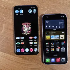 Dwa smartfony, jeden z Androidem, drugi z iOS, leżące na drewnianym blacie.