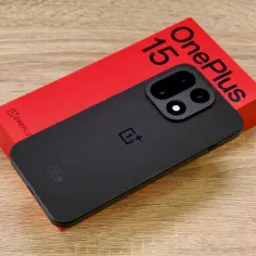 Czarny telefon OnePlus 15 na czerwonym pudełku.