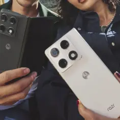 Dwie osoby trzymają telefony Motorola Razr fold. Jeden czarny, złożony, drugi biały, rozłożony.