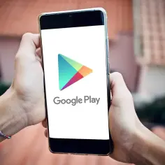 Dłonie trzymają smartfon z logo Google Play. Można tu pobrać wiele aplikacji, w tym gry i narzędzia w formacie apk.