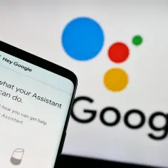 Smartfon z Asystentem Google i logo Google w tle.