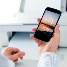 Dłoń trzyma smartfon z napisem "Sending to printer", pokazując, jak drukować z telefonu. Obok drukarka drukuje dokument.
