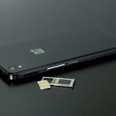 Czarny smartfon z tacką na kartę SIM i kartą pamięci obok. Dowiedz się, jak przenieść zdjęcia z telefonu na kartę pamięci.