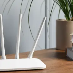 Biały router z antenkami, gotowy do zapewnienia szybkiego połączenia 4g. Obok książki i roślina w doniczce.