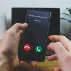 Dłoń trzyma smartfon z ekranem pokazującym "Unknown number calling...". Czy to tymczasowy numer telefonu?