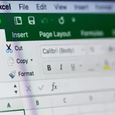 Zbliżenie na interfejs programu Excel, widoczna zakładka "Home" z opcjami "Paste", "Cut", "Copy", "Format".