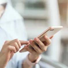 Dłonie trzymające smartfon, szukające informacji, jak wyłączyć tryb awaryjny w telefonie.