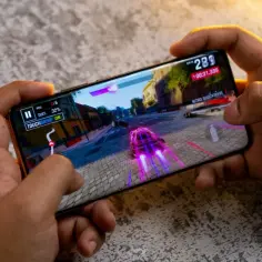 Ręce trzymają smartfon, na którym gra wyścigowa. Idealny telefon do 2500 zł do takich rozrywek.