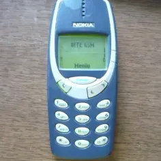 Klasyczny telefon Nokia, jeden z tych starych modeli, z zielonym wyświetlaczem pokazującym "BITE GSM" i "Menu".