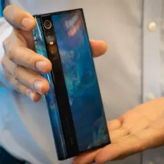Ręce trzymające futurystyczny telefon Xiaomi Mi Mix Alpha z niebieskim, marmurkowym wzorem na obudowie.