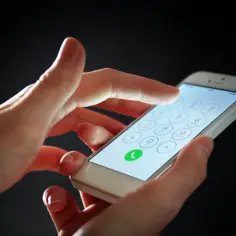 Dłoń wpisuje numer na telefonie, szukając sposobu, jak namierzyć numer telefonu.