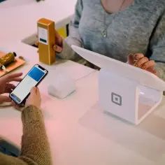 Kobieta płaci telefonem, ekran pokazuje "Face ID". Czy można cofnąć blik? Zakup kosmetyku w sklepie.