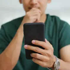 Mężczyzna zamyślony nad telefonem, szuka informacji jak włączyć autokorektę Samsung.