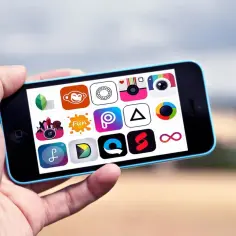 Dłoń trzyma smartfon z widokiem na ekranie wielu ikon aplikacji do edycji zdjęć.