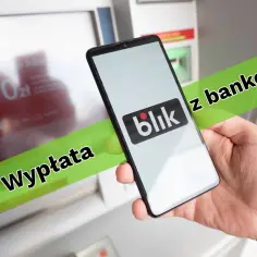 Dłoń trzyma smartfon z logo Blik przed bankomatem. Czy można wpłacić pieniądze Blikiem? Tak, ta opcja jest dostępna.