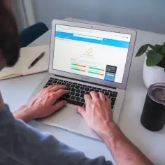 Osoba pracuje na laptopie, na ekranie którego widoczny jest wynik testu prędkości strony internetowej.