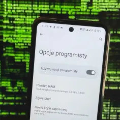 Ekran telefonu z opcjami programisty na tle zielonego kodu.