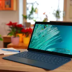 Tablet Lenovo z klawiaturą i rysikiem na drewnianym biurku, obok otwartego notatnika.