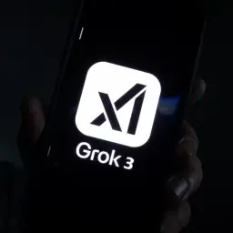 Na ekranie telefonu widoczny jest biały kwadrat z czarnym symbolem przypominającym literę "M" lub "X" oraz napis "Grok 3".