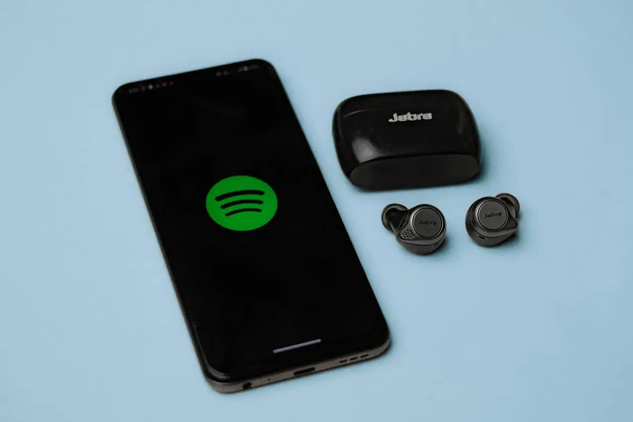 Telefon z logo Spotify i słuchawki Jabra. Zastanawiasz się, jak zrezygnować z Spotify Premium?