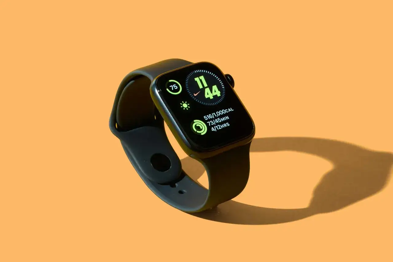 Smartwatch z zielonym ekranem wyświetlającym dane o aktywności: 75, 11:44, 516/1000 kcal, 73/45 min, 4/12 hrs. Aplikacja zdrowie monitoruje postępy.