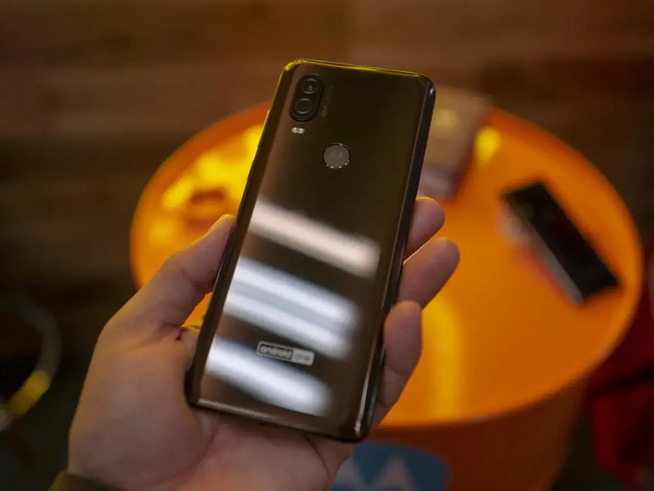 Dłoń trzyma błyszczący tył telefonu Motorola One Vision z podwójnym aparatem i logo Android One.