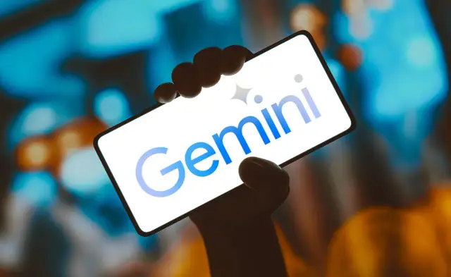 Dłoń trzyma smartfon z logo Gemini. Aplikacja Gemini otwiera nowe możliwości.